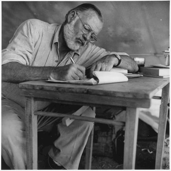 Ernest_Hemingway_Writing_at_Campsite_in_Kenya_-_NARA