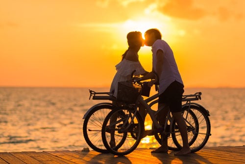 Couple on bikes, kissing on the beach